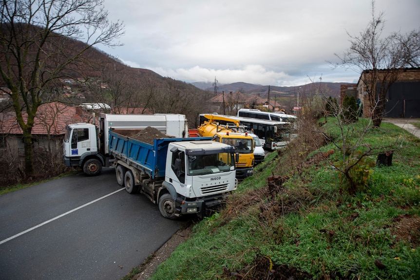 Several heavy vehicles parked across a local road.