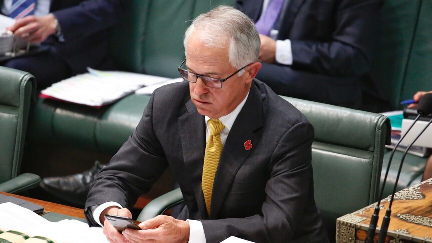 Prime Minister Malcolm Turnbull checks his phone.
