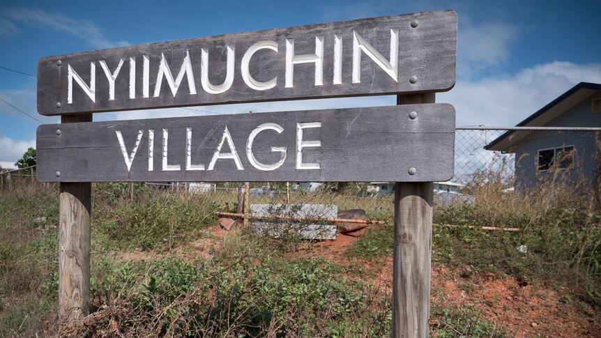 A timber housing estate sign with the words 'Nyiimuchin Village'.