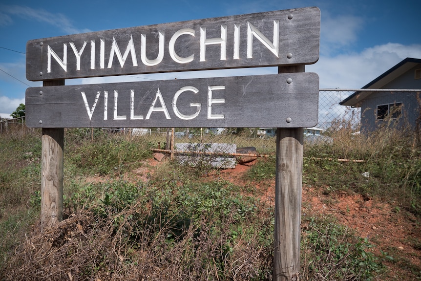 A timber housing estate sign with the words 'Nyiimuchin Village'.