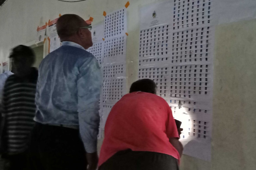 Early voters in West Honiara, Solomon Islands, checking for their names on a voter list.