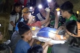A survivor of the landslide is carried out on a stretcher by several rescuers