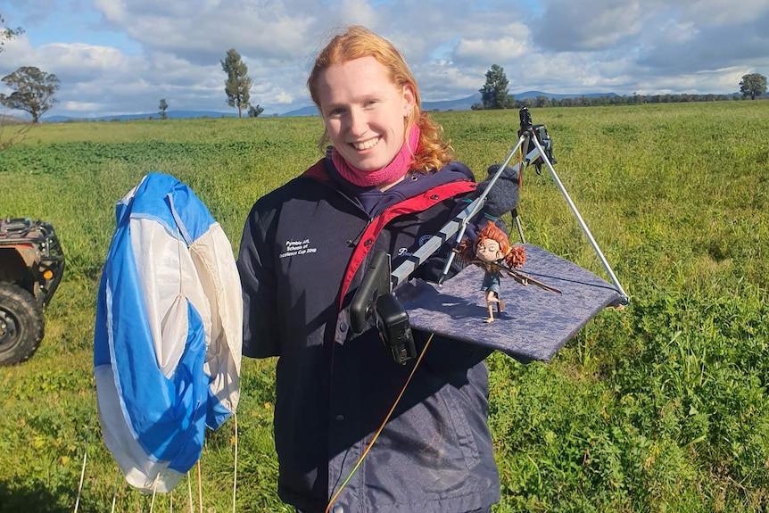 Alex Johnson standing in a farm paddock holding a high-altitude balloon.