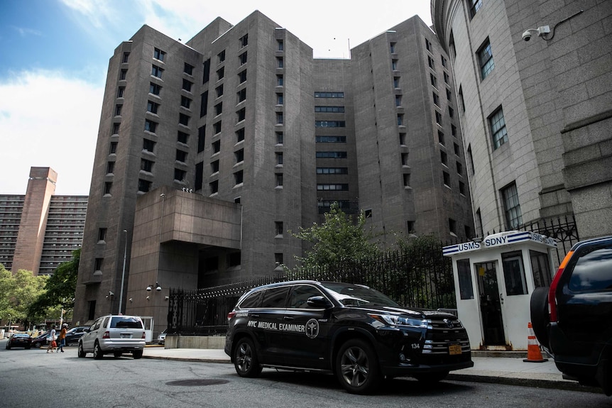 A medical vehicle in front of a large grey building.