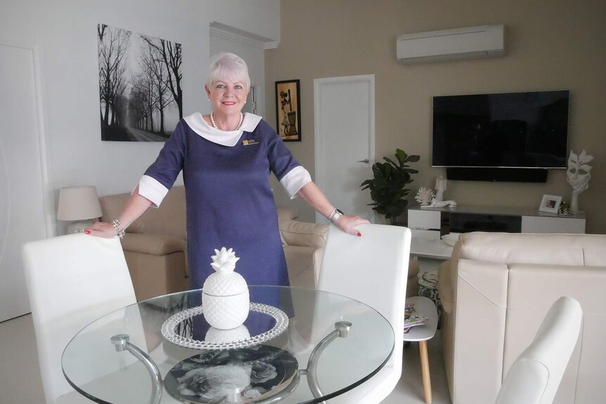 Realtor Glenda Worrall stands inside a tastefully decorated loungeroom