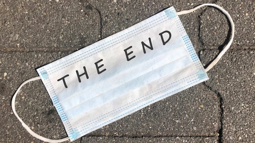 Facemask outside on concrete pavement with "the end" written inside it
