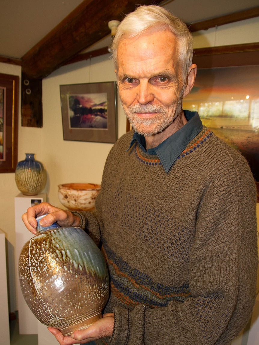 John Dermer, centre of camera standing, holds a pottery vase.