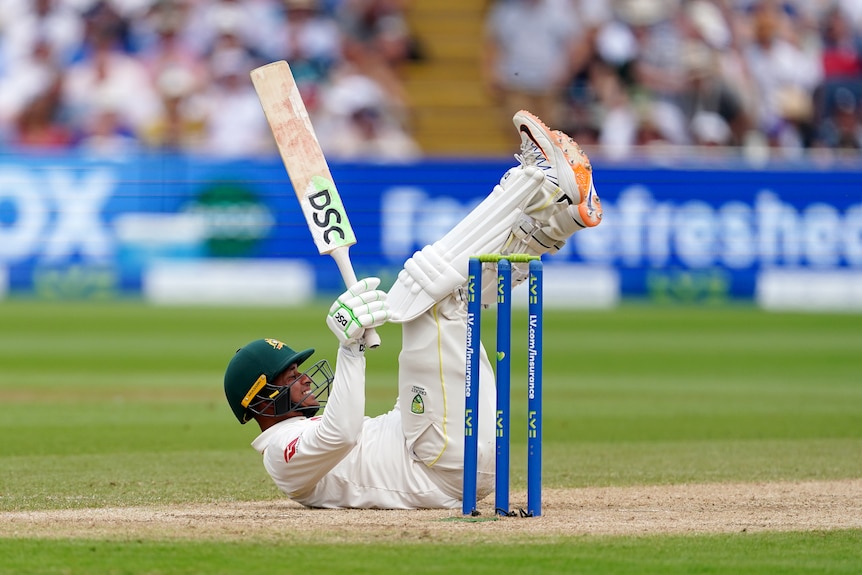 Usman Khawaja lays on his back in front of the stumps and smiles
