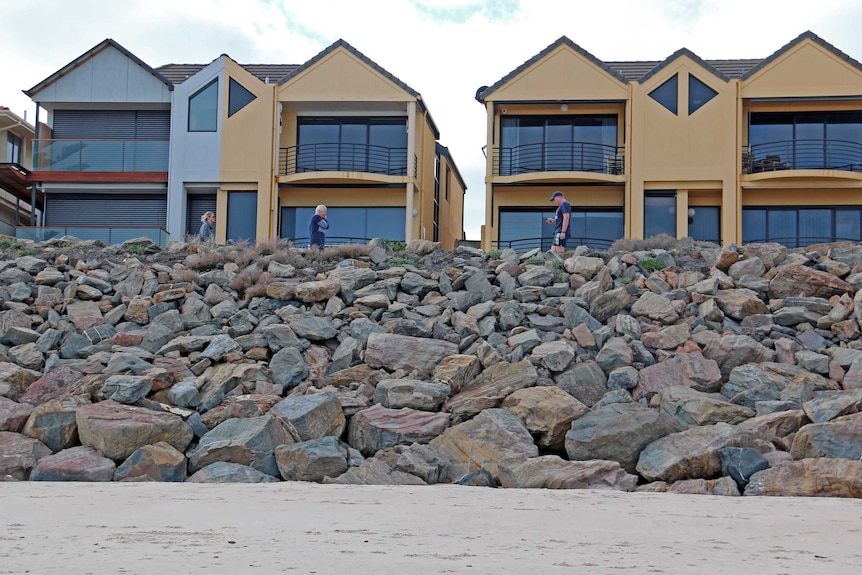 A row of townhouses beachside near a rock wall