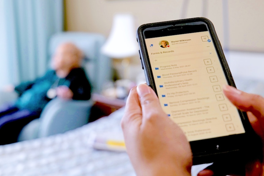 A close-up of a person using an app that lists forms and records for an aged care resident.