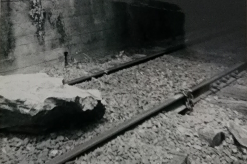 A boulder on railway tracks shot in black and white