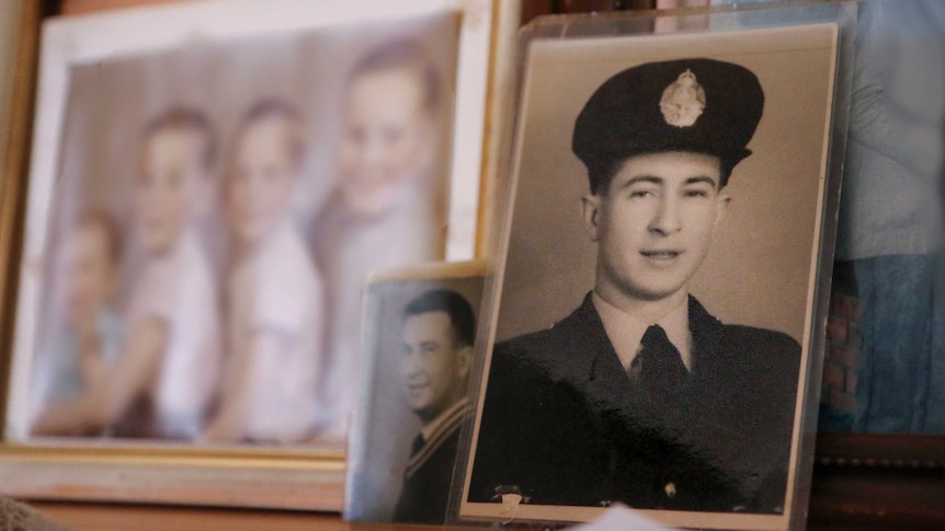 Three family photos on a cabinet, with the focus on a photo of a young man wearing a police uniform.