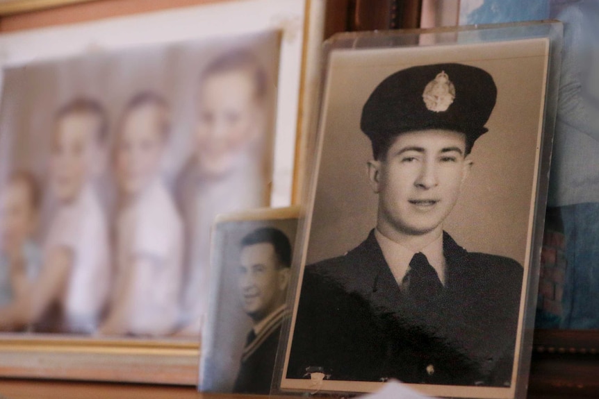 Three family photos on a cabinet, with the focus on a photo of a young man wearing a police uniform.