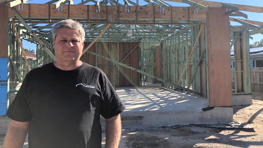 Man stands in front of a house being built