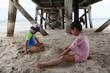 Children play on the sand under a jetty at Semaphore Beach