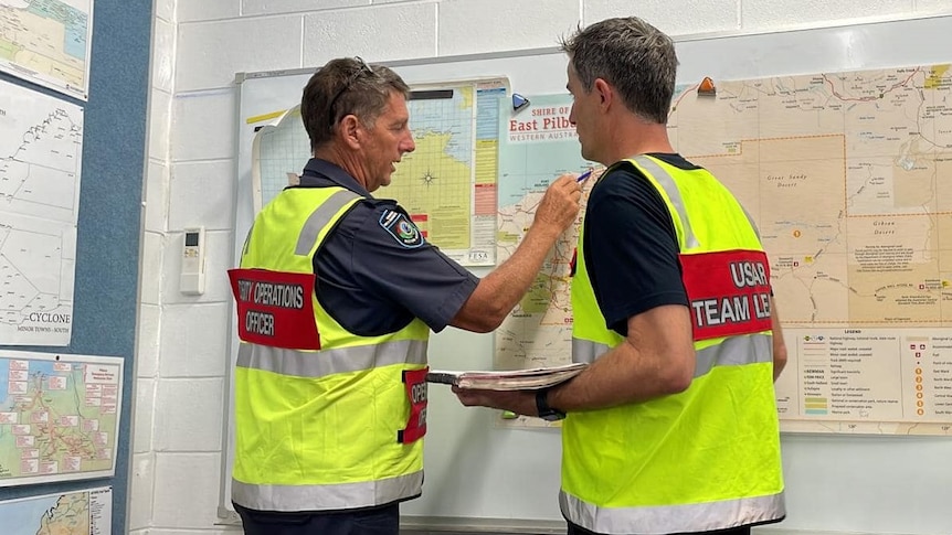 Urban Search and Rescue team members pointing to a map as they discuss plans for the arrival of the cyclone.