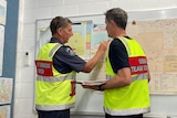 Urban Search and Rescue team members pointing to a map as they discuss plans for the arrival of the cyclone.