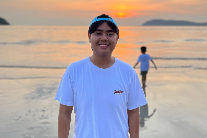 Ayman Hareez Muhammad Adib standing on a beach with a sunset in the background. 