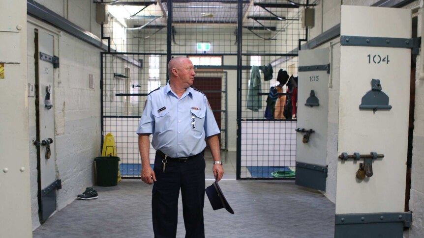 A guard looks inside a cell.