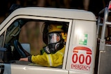 A passenger-side window open to a firefighter wearing a large gas mask.