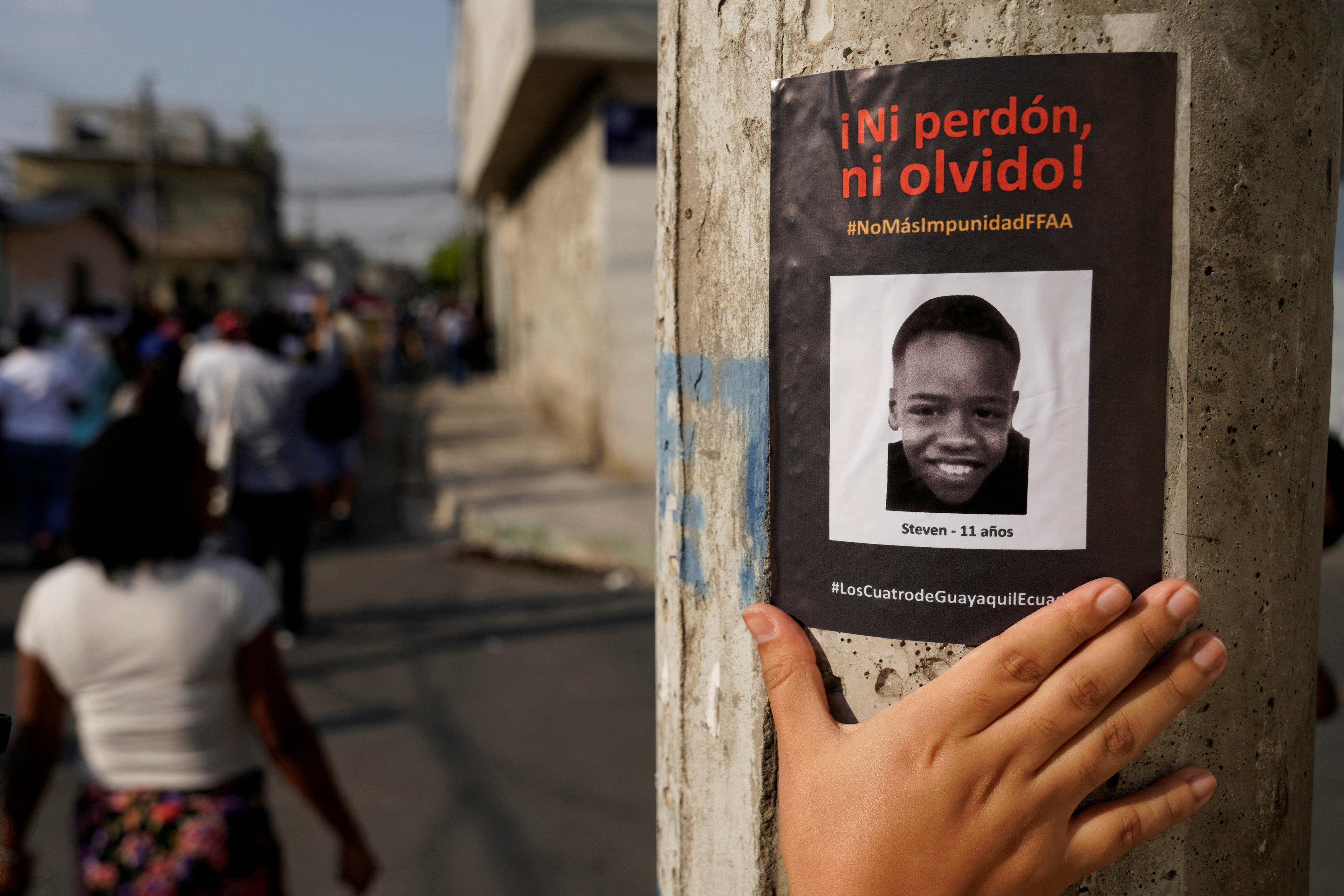 Uma pessoa toca um adesivo em um poste que diz 