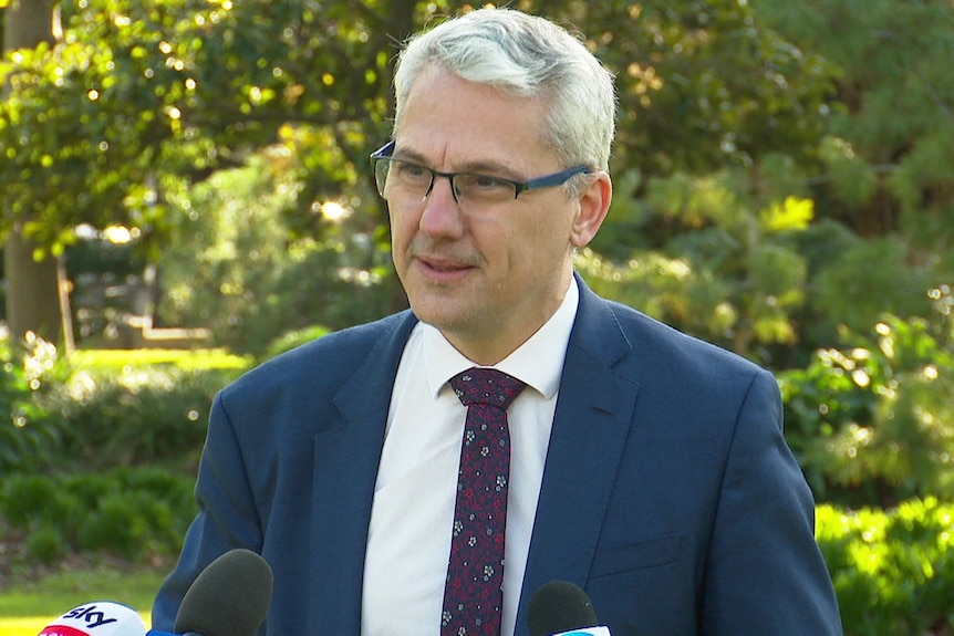 a man wearing glasses, a suit and tie. 