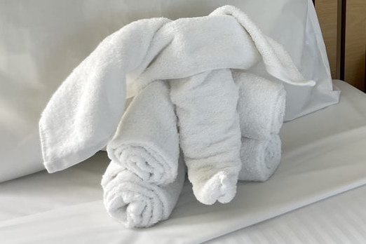 Two beds side by side with white bath towels that have been folded into the shape of elephants