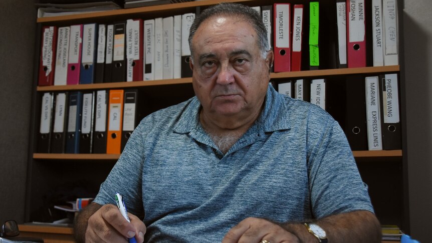 A photo of Northern Territory builder George Milatos sitting at his desk, looking at the camera.