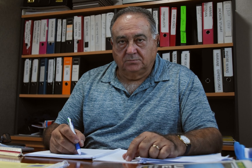 A photo of Northern Territory builder George Milatos sitting at his desk, looking at the camera.