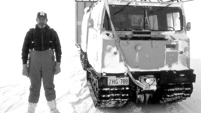 Man standing in snow alongside large vehicle