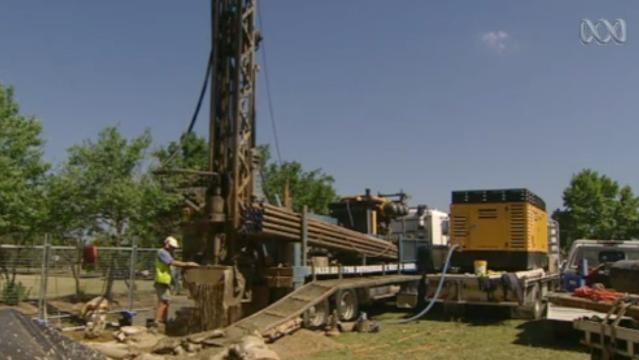 A man stands beside a large drilling machine