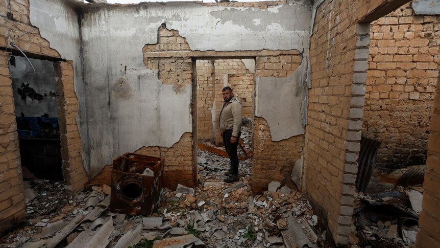 A man stands in a house burned by Russian soldiers in the village of Blahodatne.