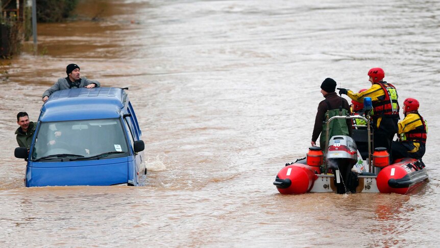 Rescue dinghy and van pass on a flooded street.