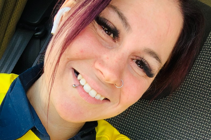 A woman wearing high-vis smiles for a selfie