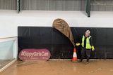 Bodye Darvill is standing on a muddy floor next to a muddy sign saying gippy girls can and safety cone