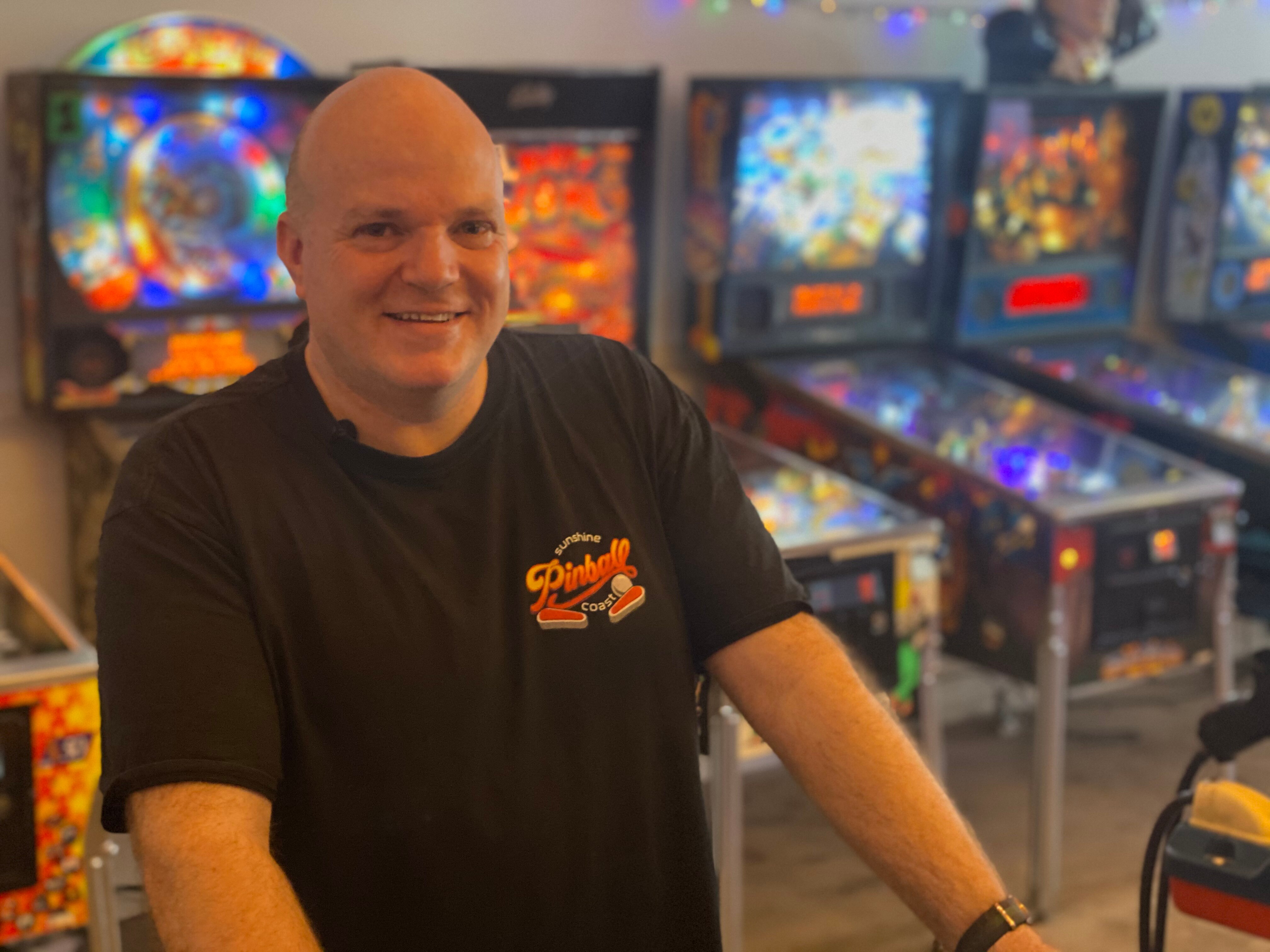 man standing in front of pinball machine