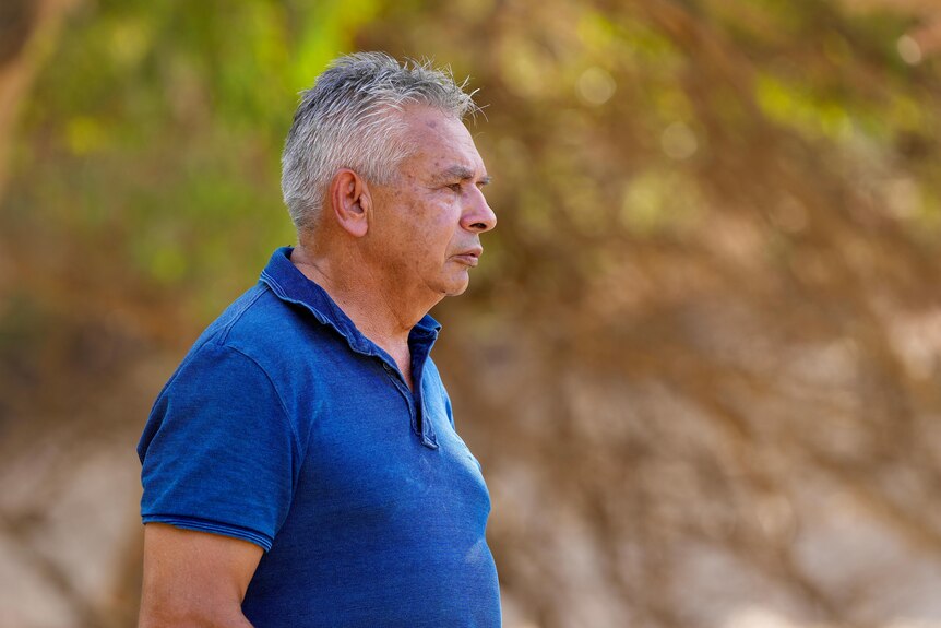 An Aboriginal man with a blue shirt staring at the Darling River.