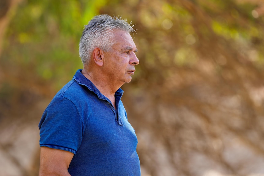 An Aboriginal man with a blue shirt staring at the Darling River.