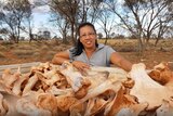 Woman standing behind a ute tray filled with camel bones.