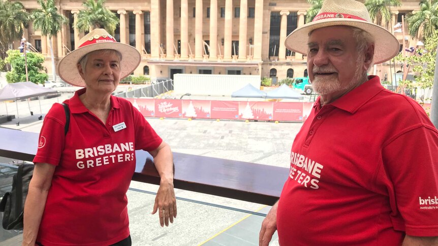 Two older people, a man and woman, stand together outside City Hall in Brisbane.
