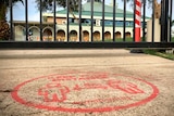 A social distancing sign on the ground in front of the gates of a school.