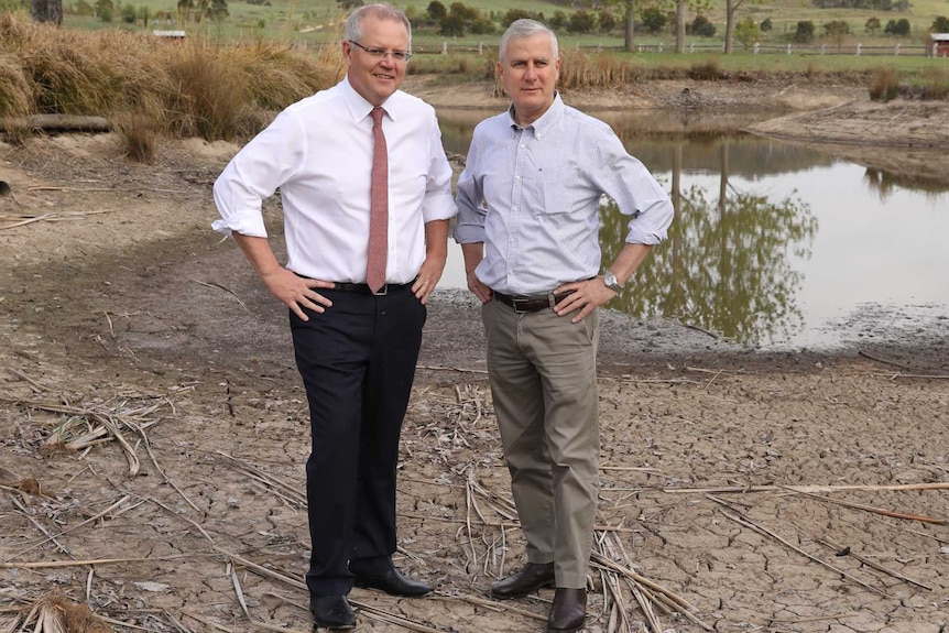 Scott Morrison and Michael McCormack stand on the dried out part of a receding dam