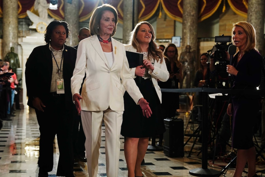 Woman wearing a white suit walking indoors.