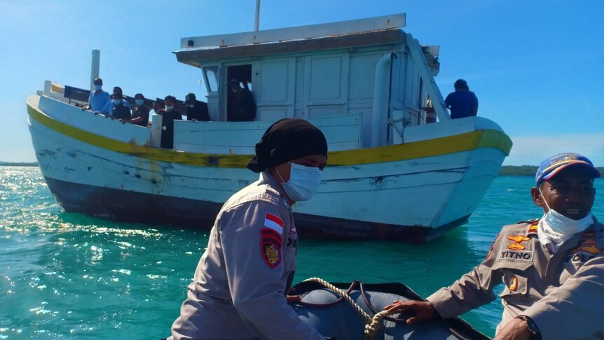 Indonesian police wear face masks as they head towards a wood boat.