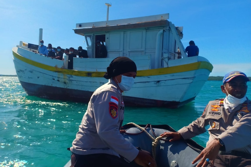 Indonesian police wear face masks as they head towards a wood boat.