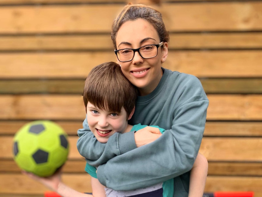 Sarah Goulding embraces her son, who is holding a soccer ball.