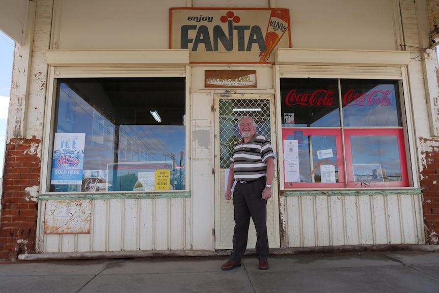 A man standing outside an old high-street corner store