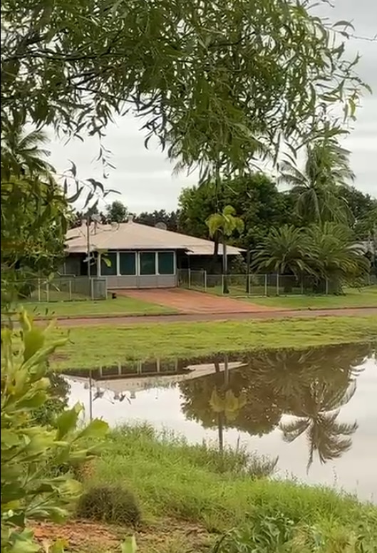 Casa con pasto verde y agua del aumento del nivel del río al otro lado de la calle