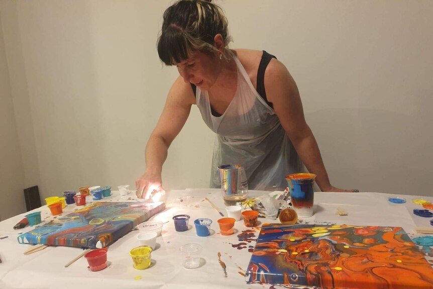 Robyn Adams painting a canvas on a white table