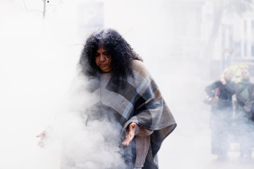 Donna Kerr stands, shrouded in smoke from an Aboriginal smoking ceremony.
